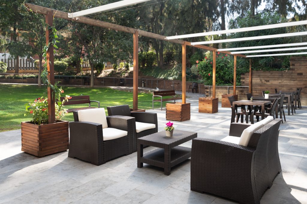 Terraza exterior con mesas y sillas rodeada de jardín